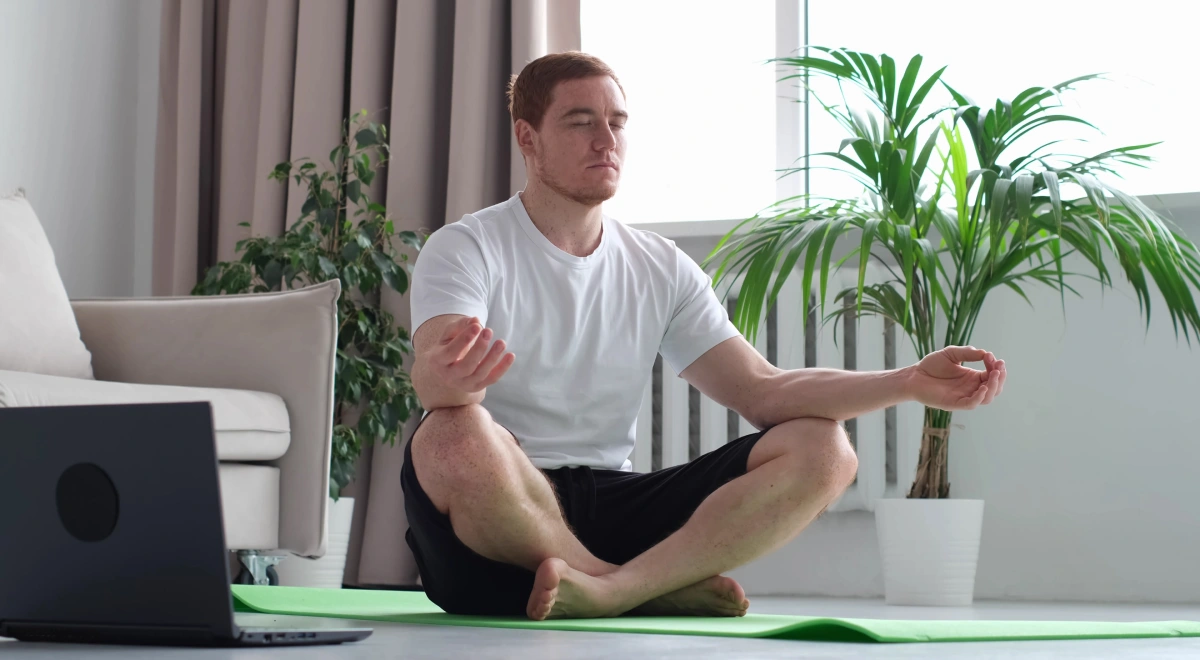 Practicante siguiendo una clase de yoga online en directo desde el salón de casa
