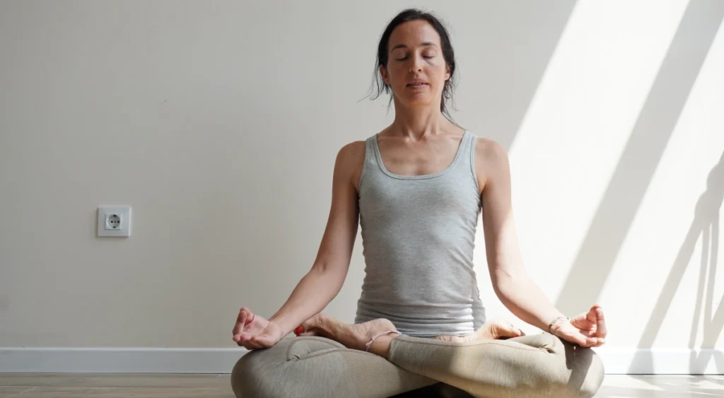 Practicante sentada en meditación en la sala de Lighthouse Yoga