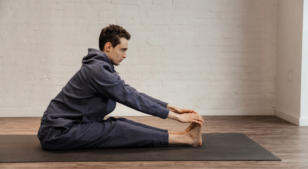 Alumno de una formación de yoga trabajando una flexión sentada sobre la esterilla