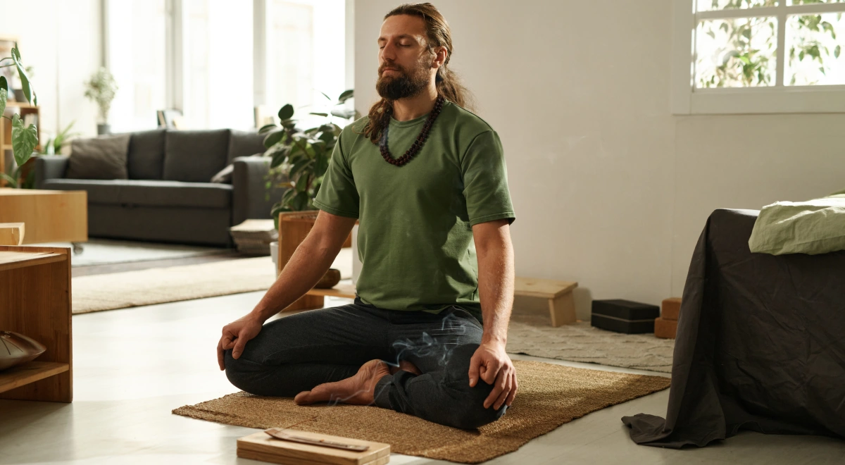 Hombre sentado en loto meditando en un espacio de práctica tranquilo