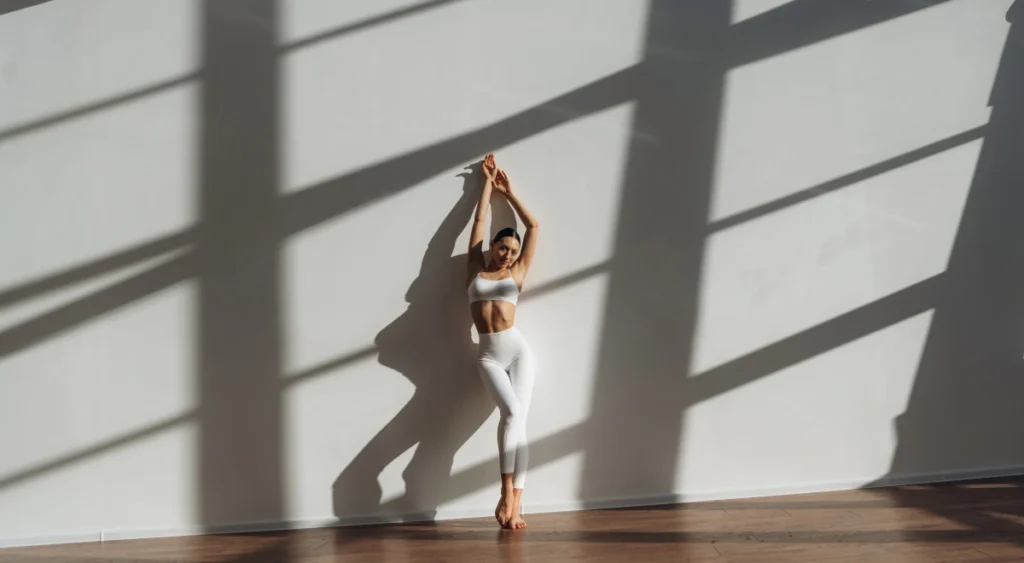 Practicante de yoga apoyada en la pared de un estudio con luz natural